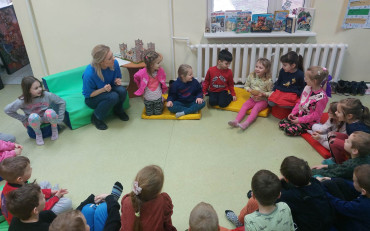 Dzieci siedzą w kole wraz z bibliotekarką