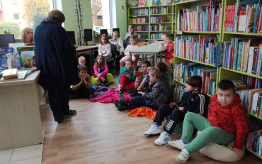 Uczniowie pierwszej klasy w części biblioteki przenaczonej dla dzieci słuchają pani Ani