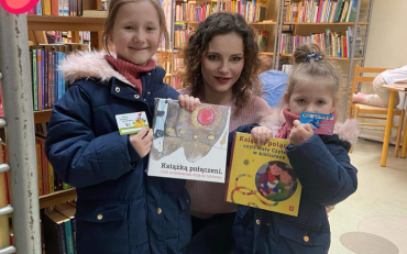 bibliotekarka i dziewczynki prezentują książeczkę