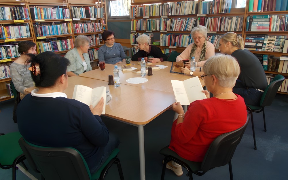 Panie siedzą przy stole i dyskutują o przeczytanej książce