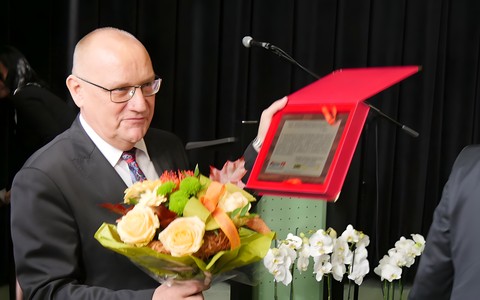 Dyrektor KBP Andrzej Ziemiński pokazuje zebranym pamiątkowy list gratulacyjny