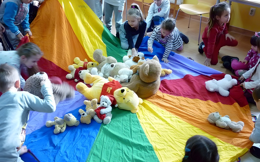 Dzieci układają pluszowe misie na chuście integracyjnej