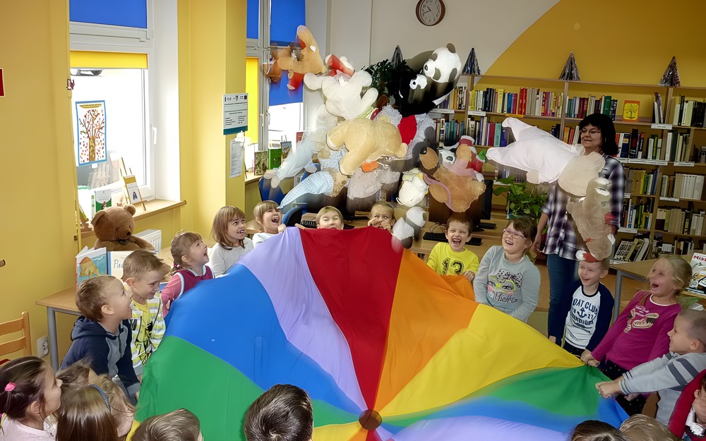 Zabawa z chustą integracyjną i misiami. Pluszaki fisiują podrzucane do góry.