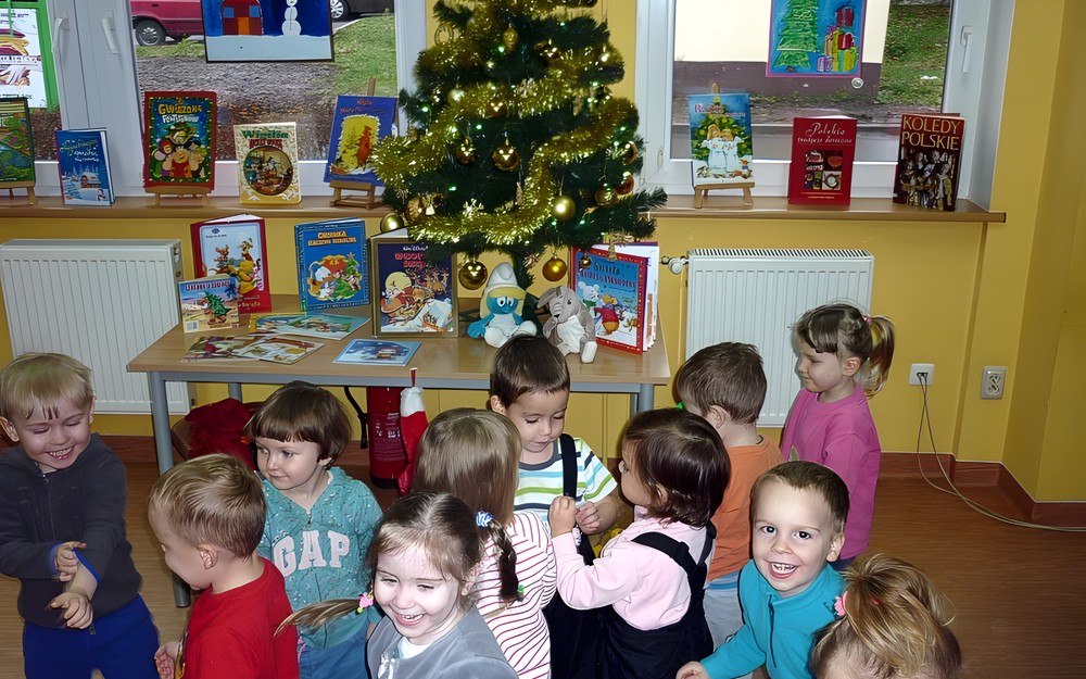 Uśmiechnięte i radosne trzylatki na tle bibliotecznej choinki