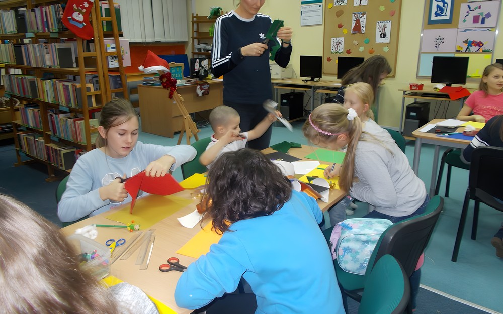 Dzieci siedząc na chuście słuchają czytanego opowiadania