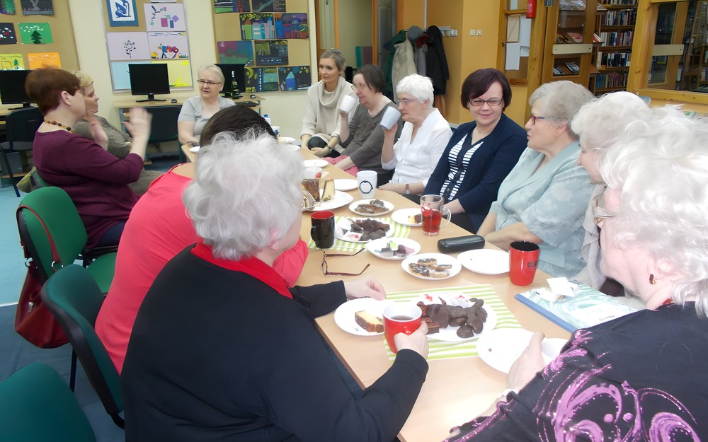 Panie siedzą wspólnie przy stole i rozmawiają