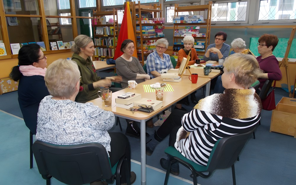 Panie siedzą przy stole dyskutując o przeczytanej książce