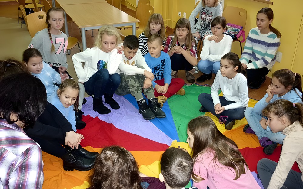 Dzieci siedzą na chuście - bibliotekarka rozmawia z nimi o uczuciach.