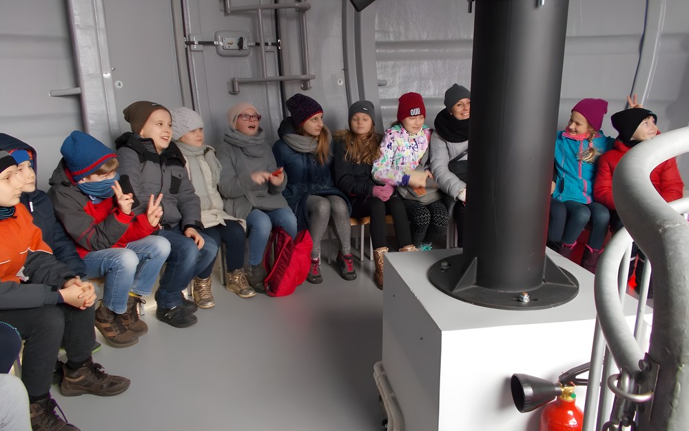 Dzieci siedzą w obserwatorium i oglądają teleskop