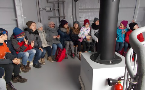 Dzieci siedzą w obserwatorium i oglądają teleskop