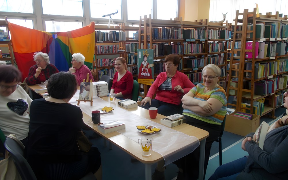 Czytelniczki siedzą przy stole wraz z bibliotekarką i dyskutują o książce w Dyskusyjnym Klubie Książek