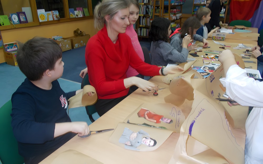 Bibliotekarka pomaga dzieciom w wykonaniu pracy plastycznej