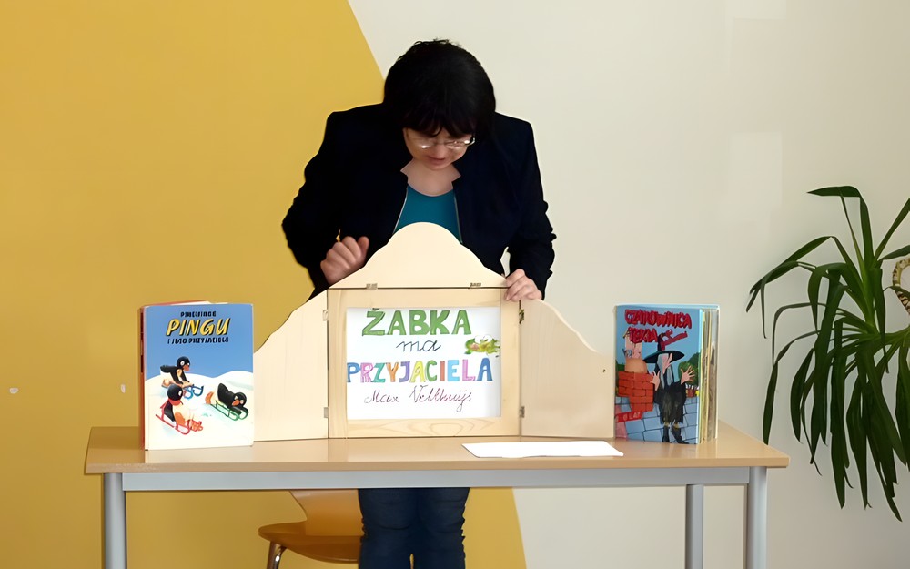 Pani Wiola przygotowuje teatrzyk Kamishibai do prezentacji historii "Żabka ma przyjaciela"