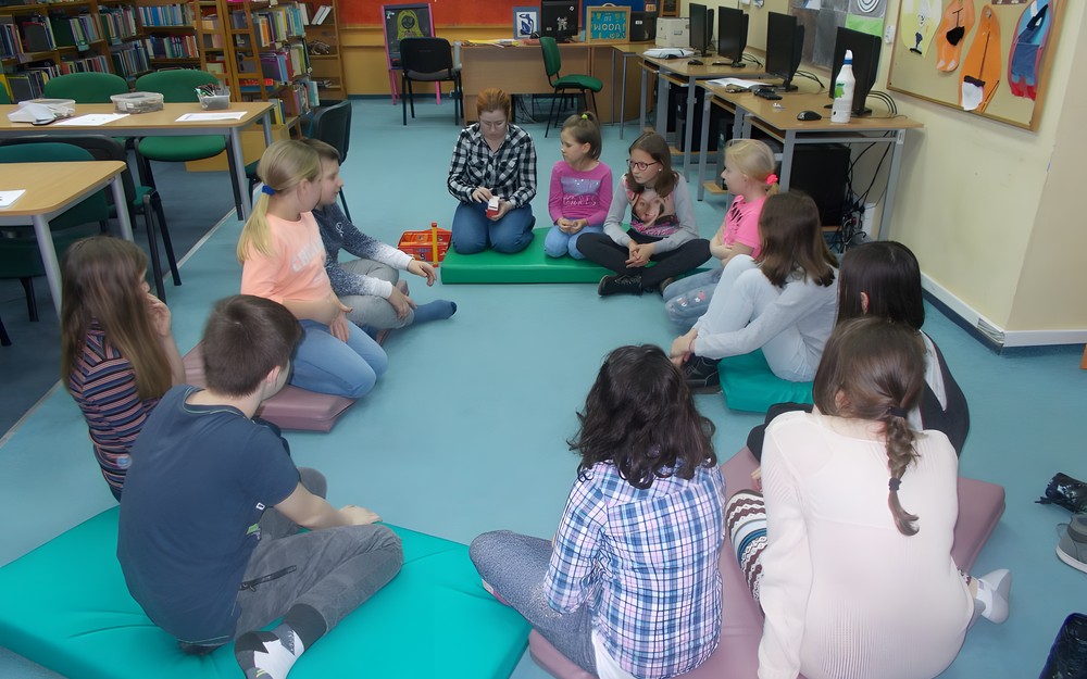 Dzieci siedzą z bibliotekakrą na materacach i grają w 5 sekund