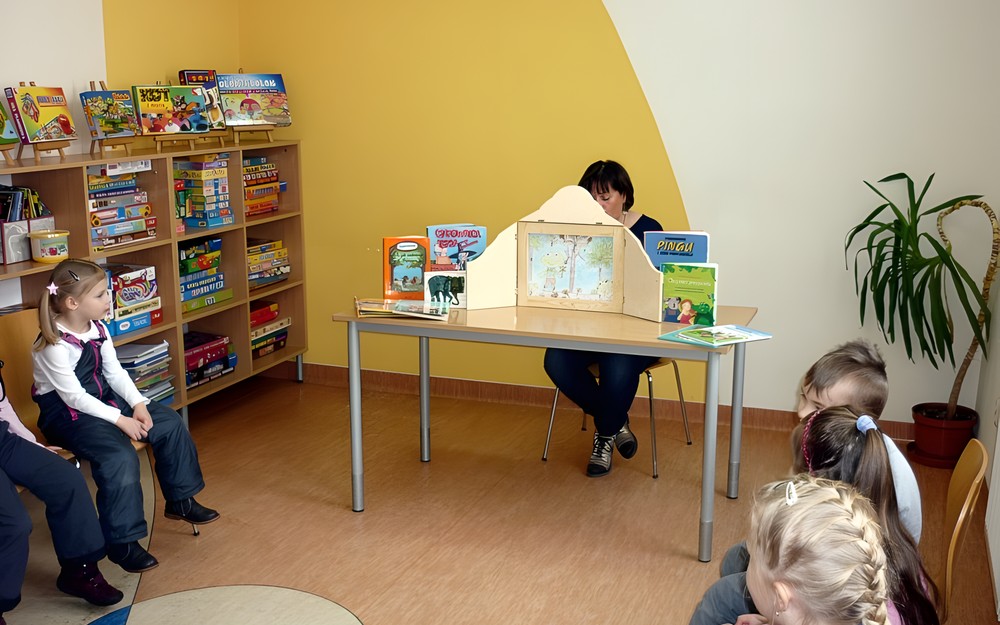 Teatrzyk Kamishibai - bibliotekarka czyta dzieciom historię żabki