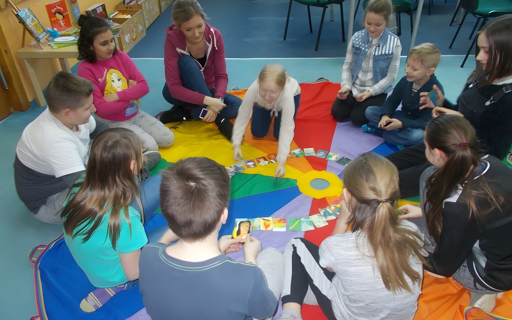 Dzieci siedzą w na chuście i wspólnie opowiadają historie