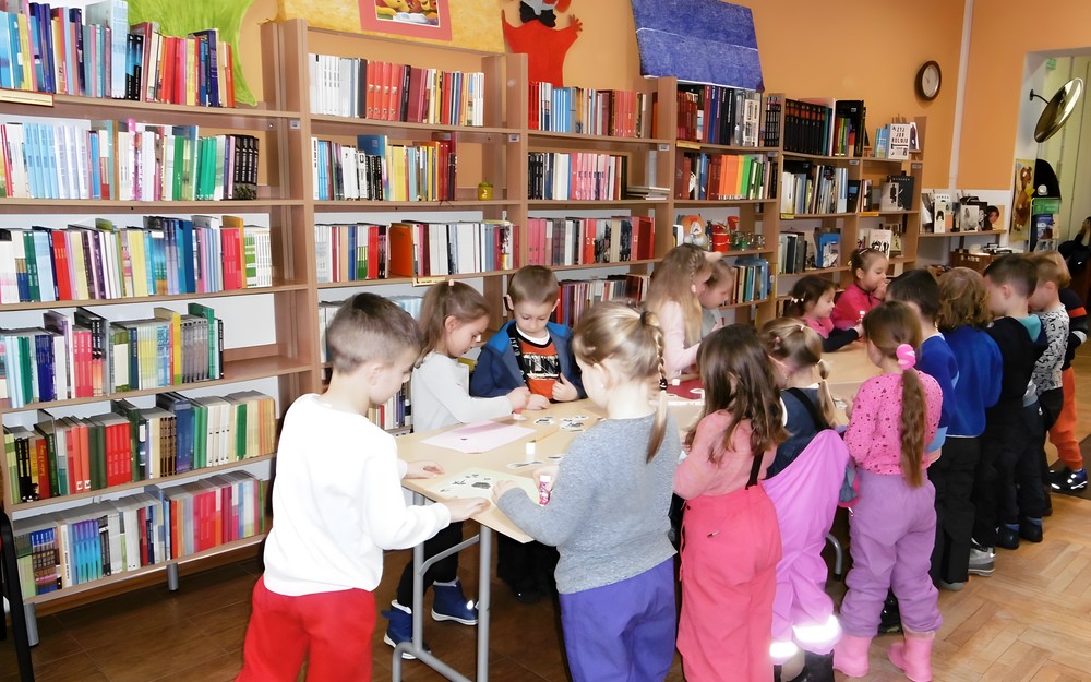 Dzieci przy stole pracują nad swoimi zadaniami.