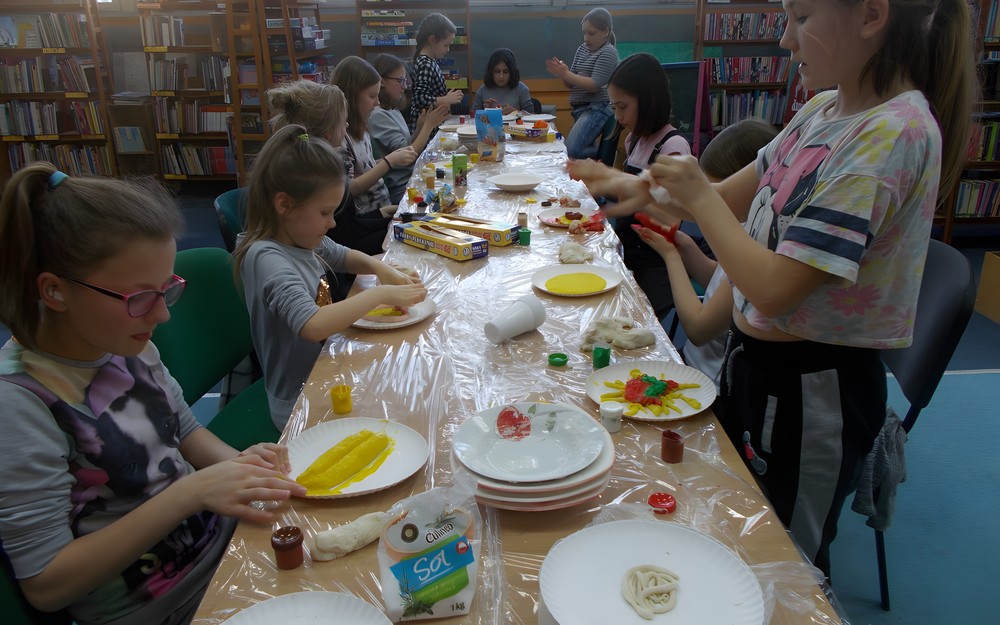 Dzieci przy stołach tworzą prace z masy solnej