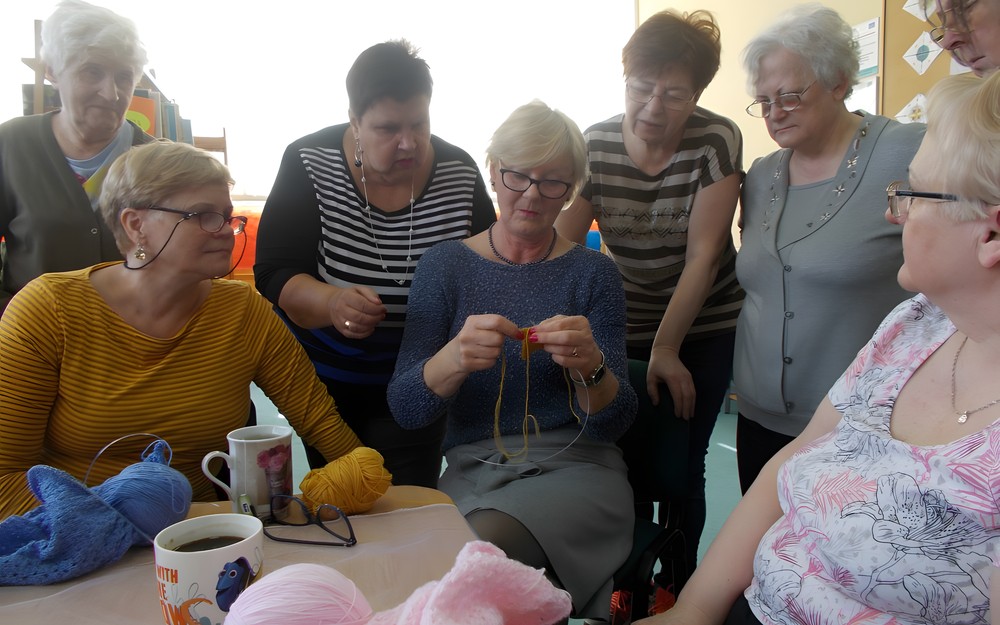 Panie przyglądają się technice robienia na drutach