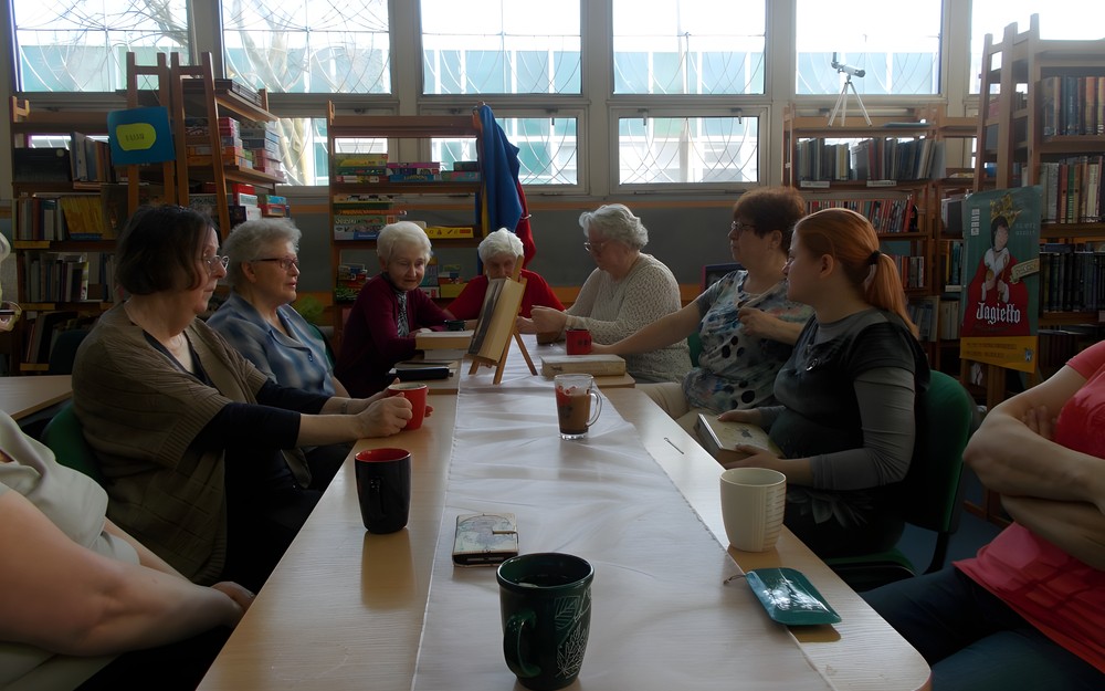 Panie siedzą przy stole i dyskutują o książce