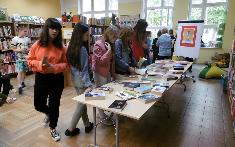 Młodzież przegląda przygotowane propozycje książkowe.