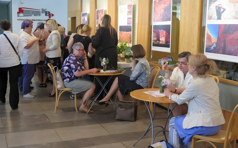 Bibliotekarki gromadzą się przed uroczystością Święta Bibliotekarza i Bibliotek. Część stoi, część siedzi przy stolikach