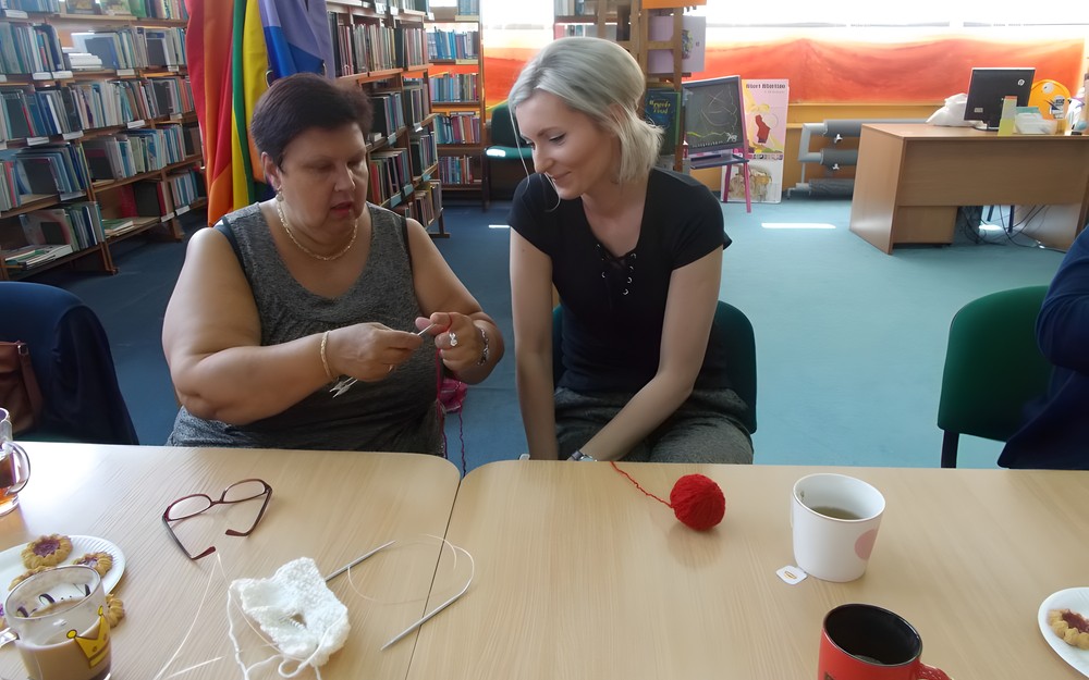 Bibliotekarka uczy się robienia na drutach od człońkini klubu