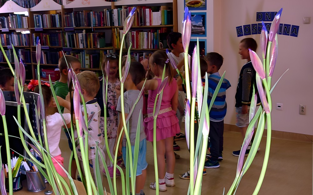 Na pierwszym planie bukiet irysów, w tle grupka dzieci