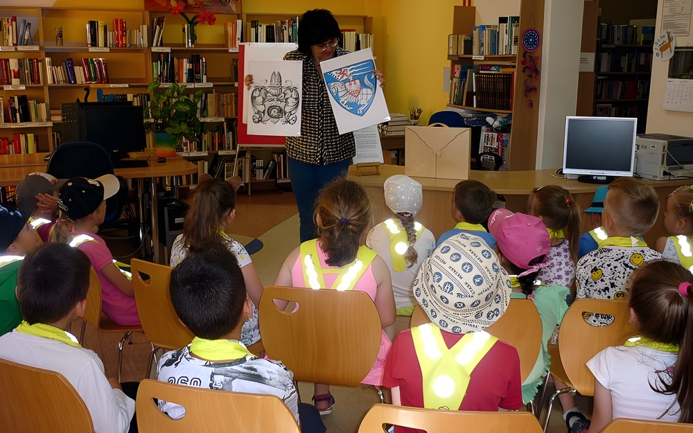 Bibliotekarka prezentuje dzieciom najstarszy i najnowszy herb Koszalina