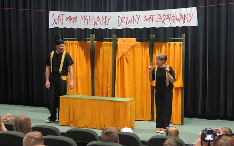 Aktorzy Teatru Władca Lalek ze Słupska (kobieta i mężczyzna) witają wyróżnionych najlepszych czytelników dziecięcych. Na scenie widnieje napis: Świat bajkami malowany. Dziwny świat zaczarowany. Przed sceną, na pierwczym planie widać publiczność