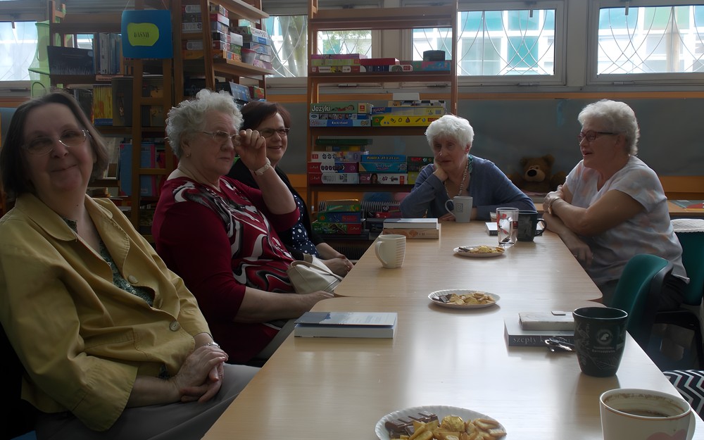 Panie siedzą przy stole i dyskutują o książce
