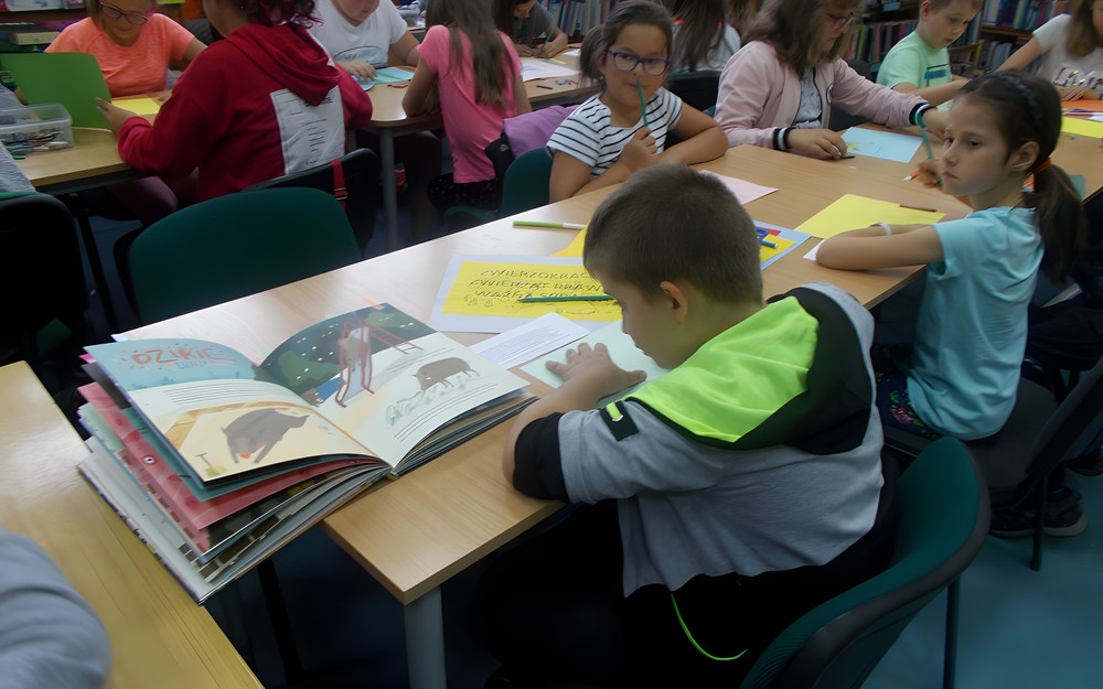 Chłopiec wykonuje pracę plastyczną inspirując się tekstem książki