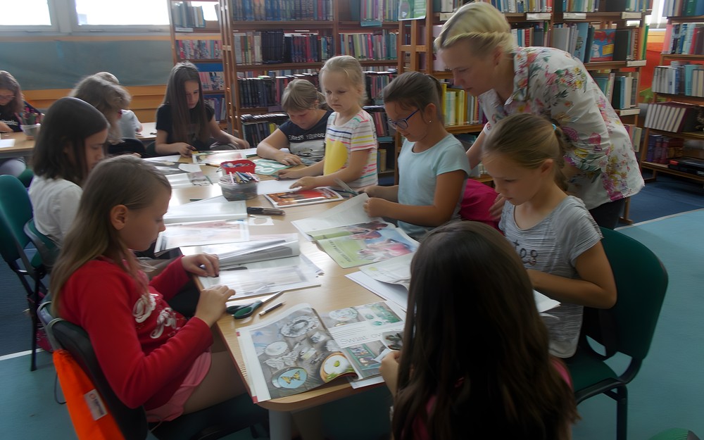 Prowadząca pomaga dzieciom w wykonywaniu pracy plastycznej