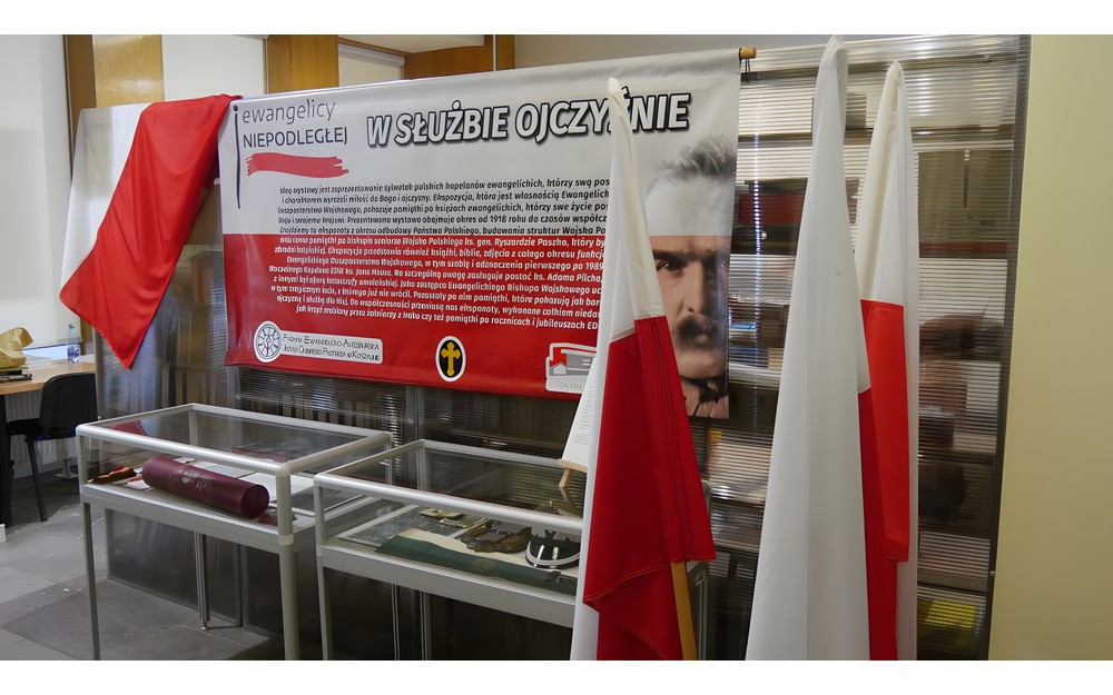 Baner reklamujący wystawę  "W służbie ojczyźnie" w otoczeniu polskich flag