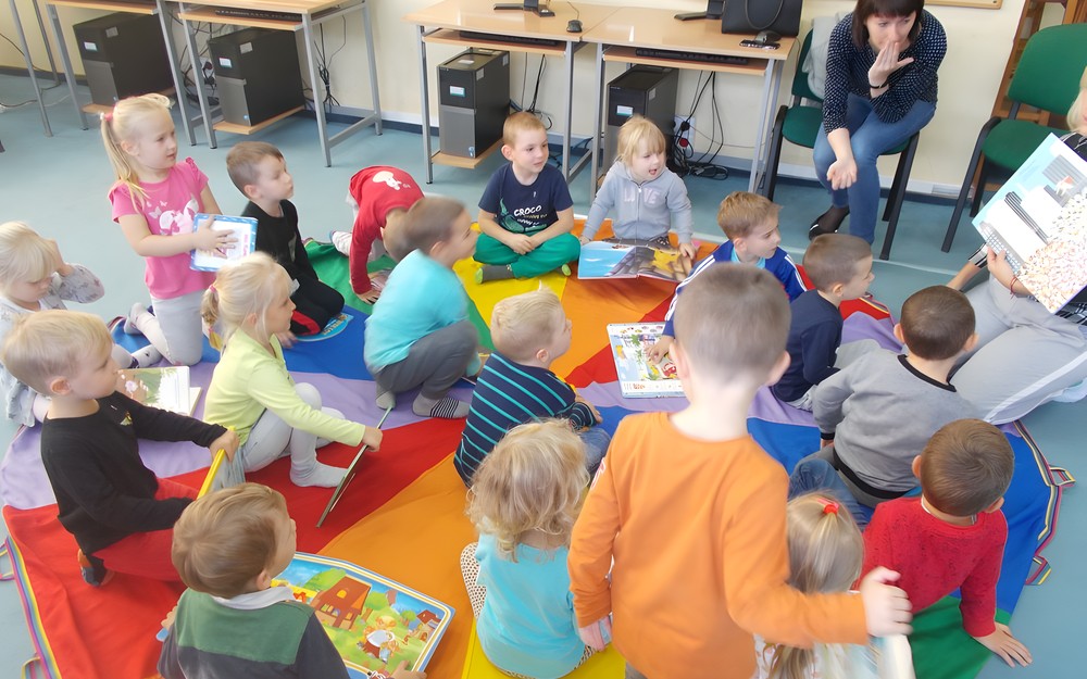Dzieci oglądają prezentowaną przez nauczycielkę ksiązkę