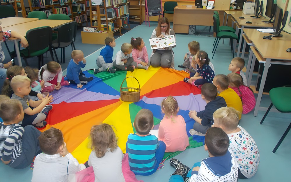 Dzieci siedzą na chuście i rozwiązują zagadki dotyczące jesieni
