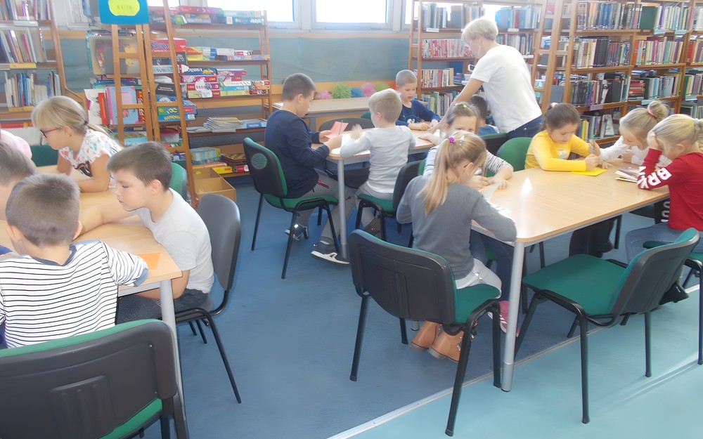 Dzieci czytają przy stołach książki