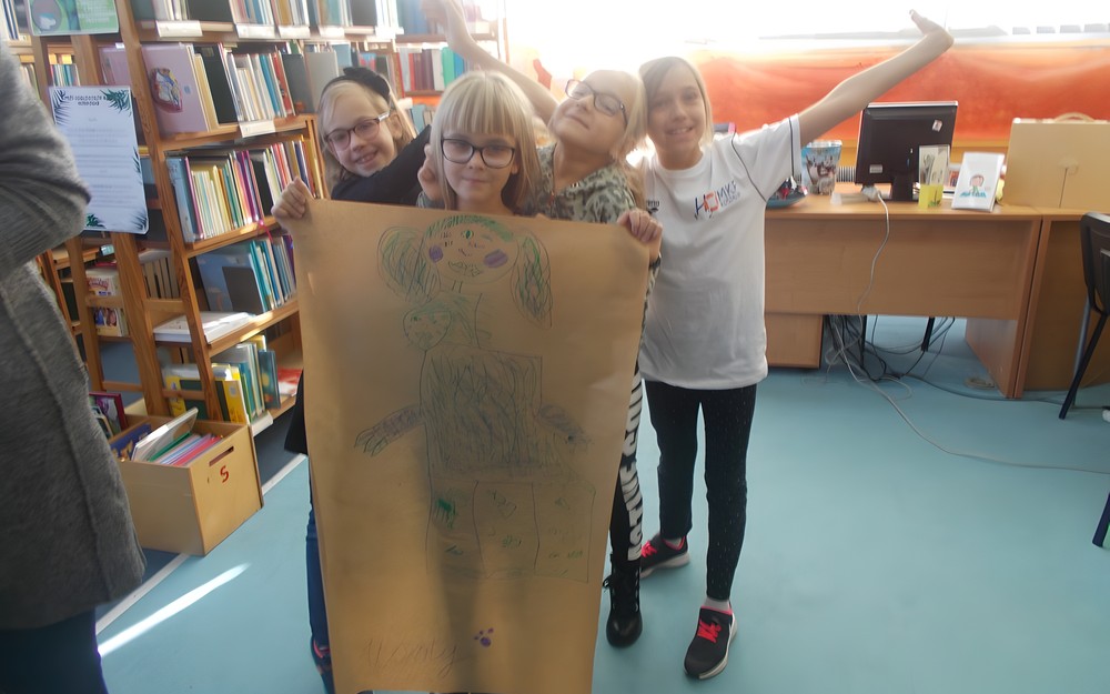 Cztery dziewczynki pozują do zdjęcia ze swoją pracą