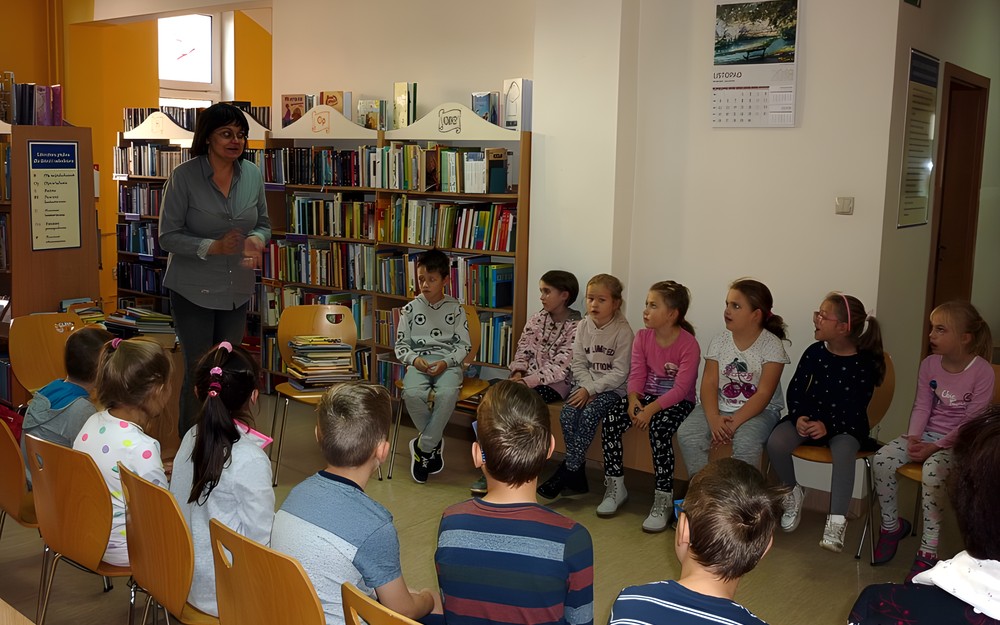 Bibliotekarka wita dzieci w bibliotece