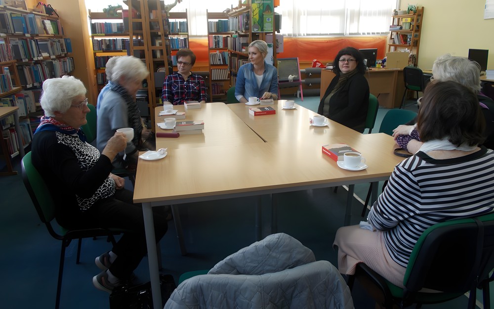 Panie siedzą przy stole i dyskutują o książce