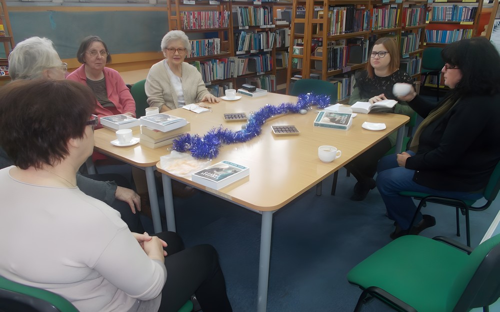 Panie siedzą przy stole i dyskutują o książce