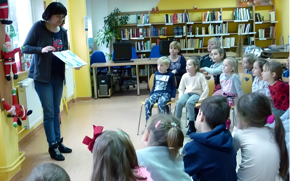 Pani Wiola pokazuje dzieciom książeczki z wystawy BAJKOWE ŚWIĘTA