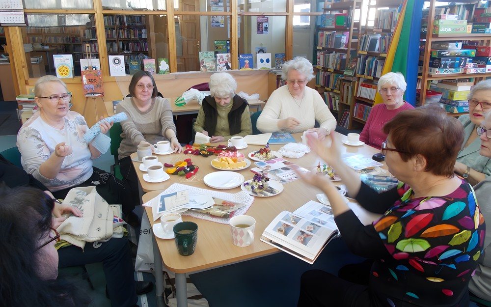 Panie dyskutują przy stole o nowych pomysłach na rękodzieła