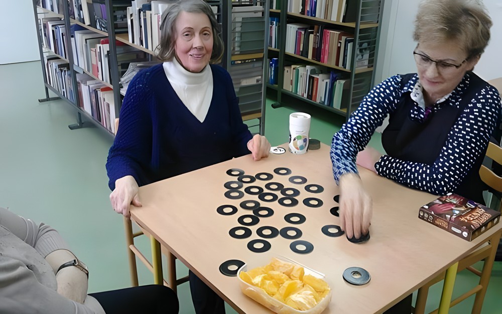 Trzy dorosłe osoby grają w grę planszową przy stole