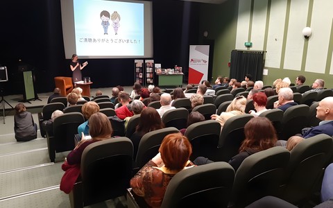 Anna Tomaszewska podczas spotkania na temat fascynującej Japonii, na przednim planie widnieje zgromadzona publiczność.