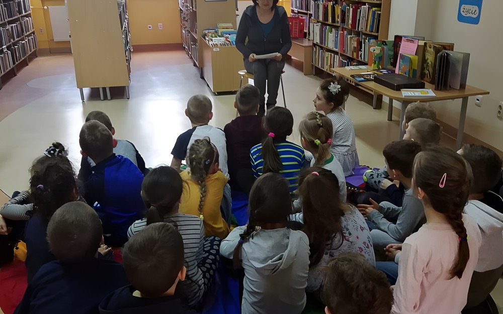 Dzieci siedzą na chuście integracyjnej - rozpoczynamy spotkanie.