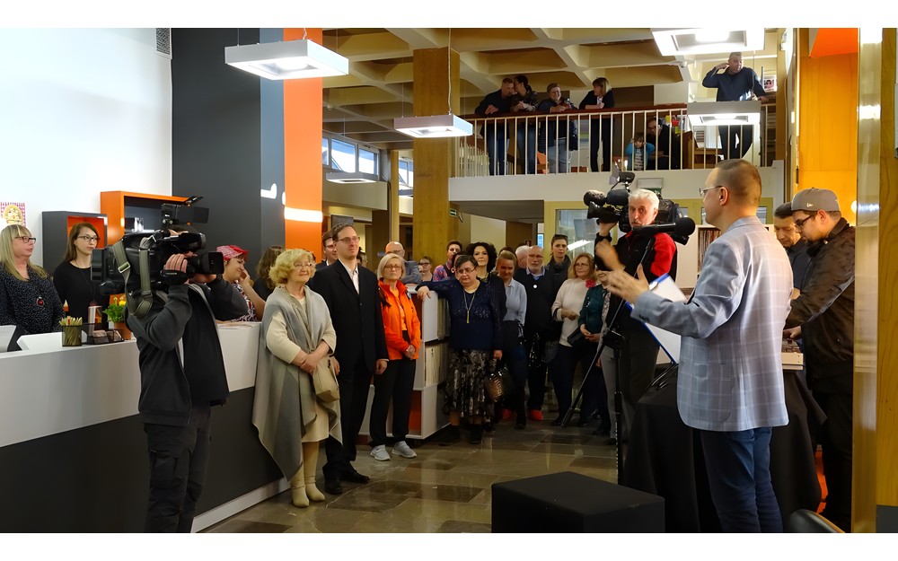 Publiczność zgromadzona na otwarciu Mediateki. Dyrektor KBP, Dariusz Pawlikowski wita przybyłych (jest zwrócony bokiem do widza)