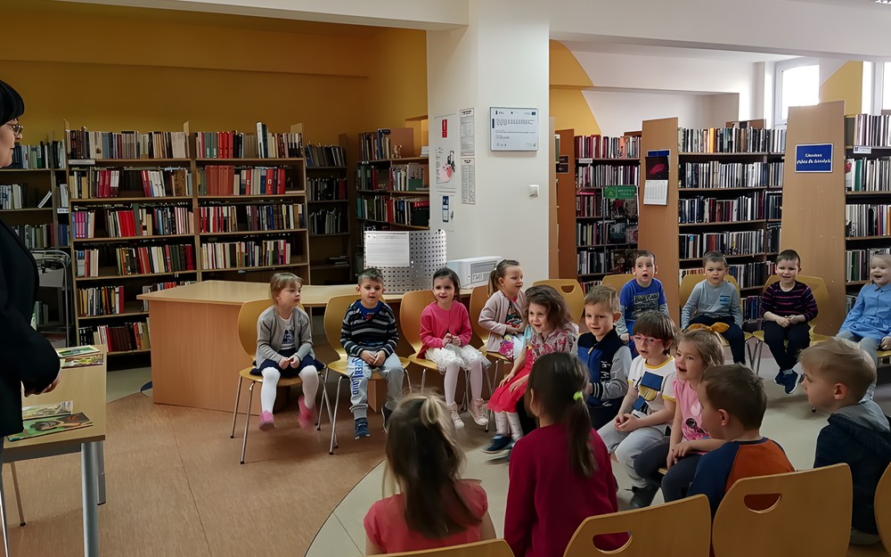 Bibliotekarka wita dzieci w bibliotece