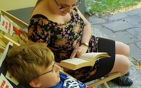 Pani Bibliotekarka głośno czyta książkę dziewczynce.