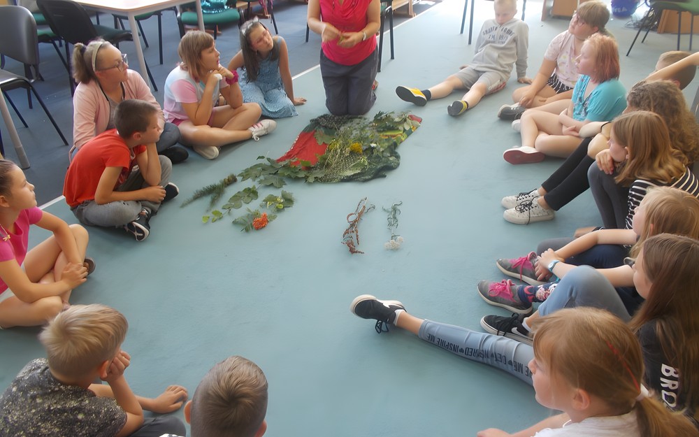 Prowadząca warsztaty pokazuje dzieciom liście poszczególnych drzew